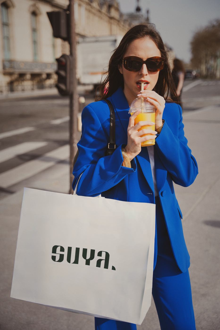 Un costume bleu et un sac SUYA blanc